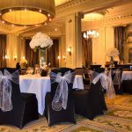 Black chair covers with white chair sashes and floral table centrepieces