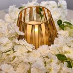 gold candleholder with LED candle sat on White floral wreath table centrepiece