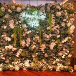 Luxury flower wall backdrop with lush greenery, white roses, and a glowing “Happily Ever After” neon sign for weddings and events.