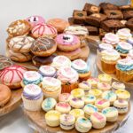 Modern dessert table display with muffins, macarons, and cupcakes at wedding reception