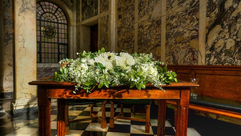 Green foliage and white roses decorating the registrar table at Stockport Town Hall
