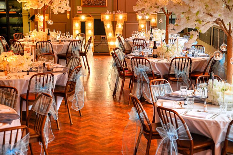 Wedding breakfast setup with blue and white theme, blossom trees, and rustic LED freestanding LOVE letters at Fountain House, Manchester