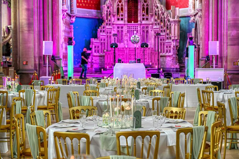 Grand candlelight setup with golden chairs and sage chiffon drapes at a wedding reception in Gorton Monastery