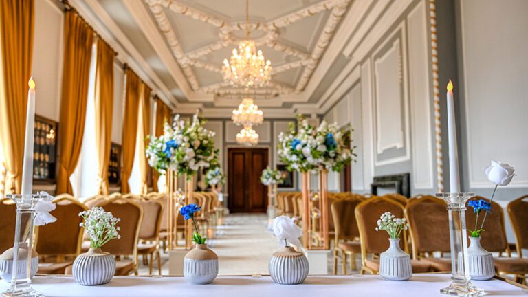 Registrar table at Manchester Hall ceremony room decorated with white bud vases, floral stems, and crystal candle holders with LED taper candles
