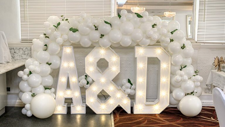 LED alphabet letters styled at wedding reception with flowers and balloons