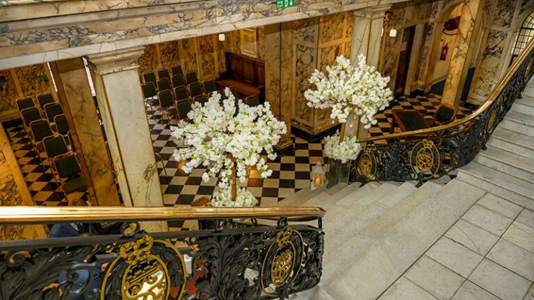 Elegant marble staircase at Stockport Town Hall adorned with two luxury blossom trees for a wedding ceremony